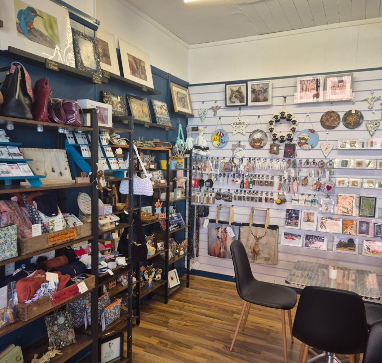White wall display and black shelf units in store full of different handmade gifts available to buy at Creative Cuppa.