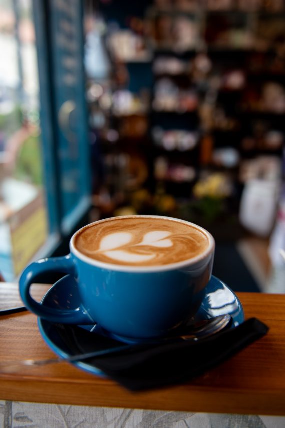 Blue coffee cup with latte art in a heart shape.