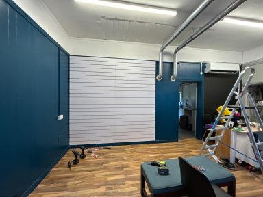 During: White slates. During: Final coat of teal on side and back walls, white slates covering the metal grate to hang products on, new laminate flooring down.