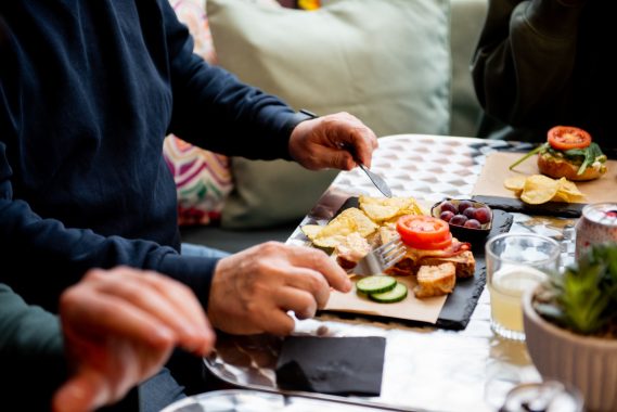 Three people enjoying open faced sandwiches at Creative Cuppa.