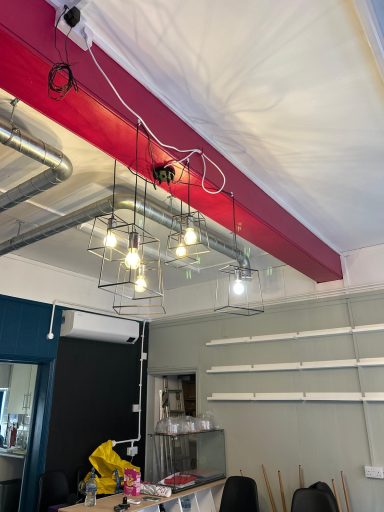 During: Pink ceiling beam. During: Room mid-renovation with a pink ceiling beam, pipework running across the ceiling, decorative pendant lights and air con unit.