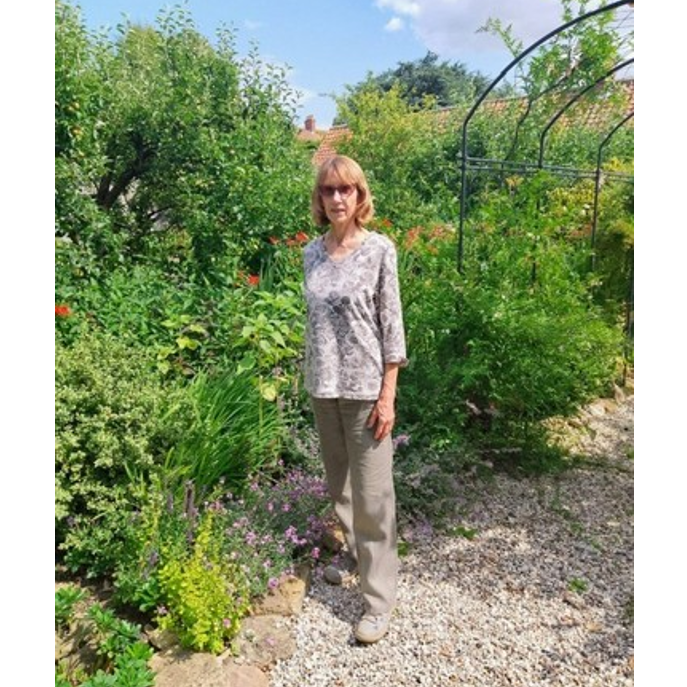 Photo of Valerie. Photo of Valerie in front of lots of green foliage on a pebbled/stone floor.