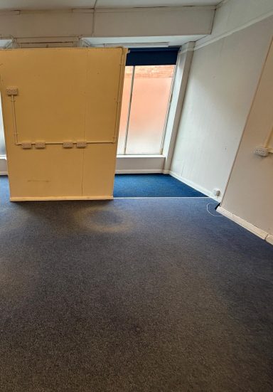 Before: Second window bay. Before: Second window bay, blue blinds, blue carpet with a darker blue walkway rug built in. Entrance way wall blocks the view of door.